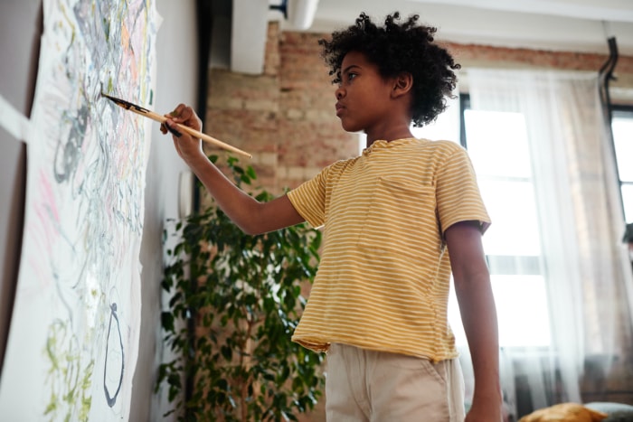 enfant en chemise rayée peinture sur papier collé au mur