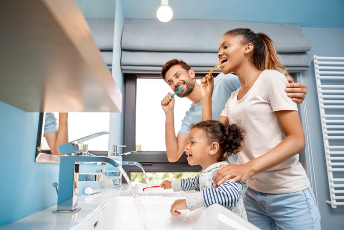 Mère, père et fille se brossent les dents dans la salle de bain