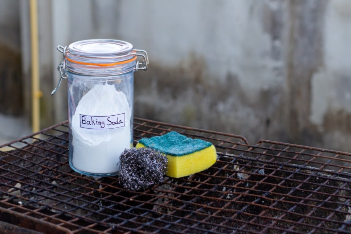 Bicarbonate de soude avec éponge et laine d'acier sur grille rouillée.