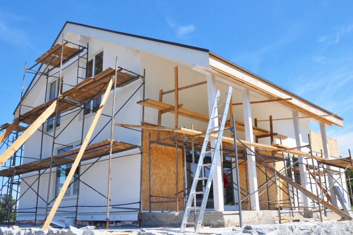 Maison blanche en cours de rénovation avec des échelles et des plates-formes.