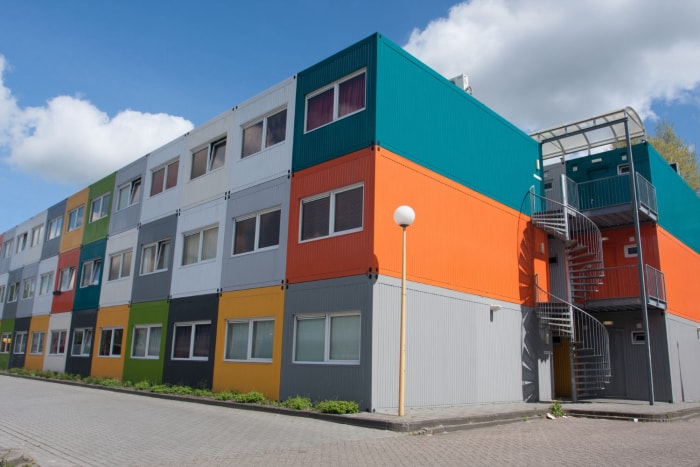 Un immeuble d'habitation composé de conteneurs multicolores empilés sur trois niveaux.