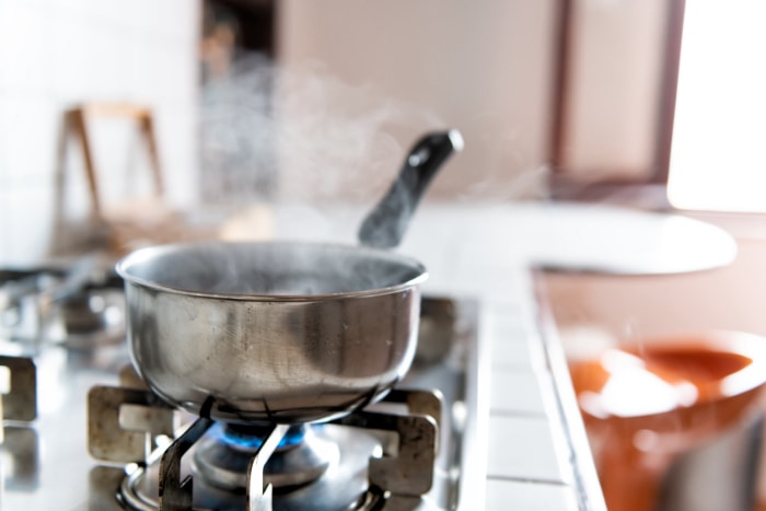 petite casserole sur la cuisinière avec de l'eau bouillante et de la vapeur montante