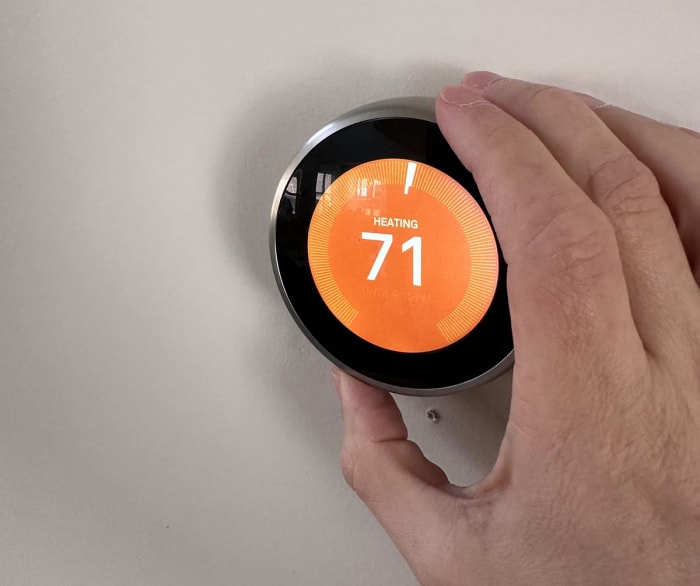 Le thermostat Google Nest Learning est installé et affiche un écran orange avec une température de 71 degrés Fahrenheit.