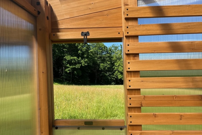 Vue de l'intérieur d'une serre en cèdre avec des fenêtres en polycarbonate texturé