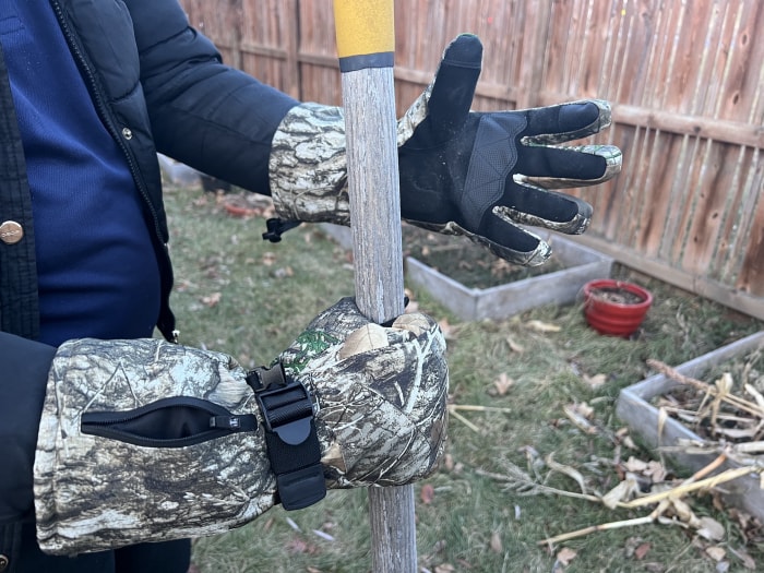 Une personne portant des gants chauffants tout en saisissant un outil à l'extérieur