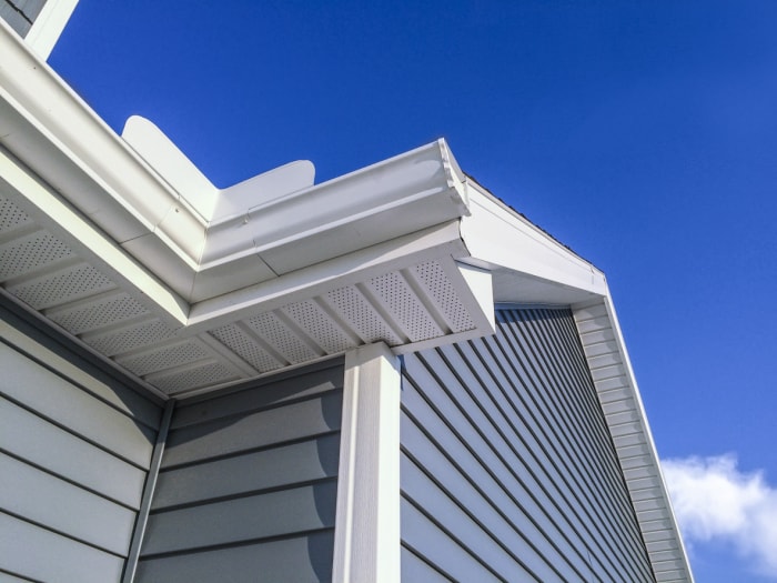 vue en contre-plongée du haut d'une maison avec un bardage en vinyle bleu sur fond de ciel bleu