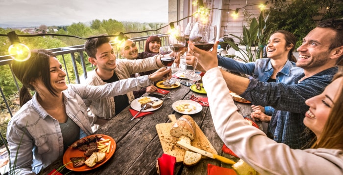 iStock-1187411357 rénovations de location à court terme amis dînant sur un balcon avec des lumières.jpg