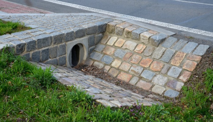 Un ponceau sous une allée est pavé de pierres.