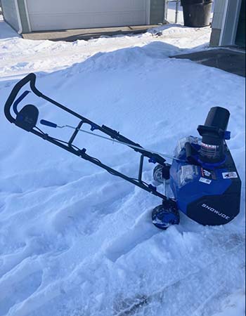 La souffleuse à neige mono-étage Snow Joe sur une surface enneigée avec plusieurs traces autour d'elle pendant les tests.