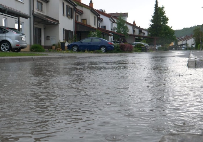 rue de banlieue pendant une tempête de pluie avec remplissage de la rue par le ruissellement des allées en béton