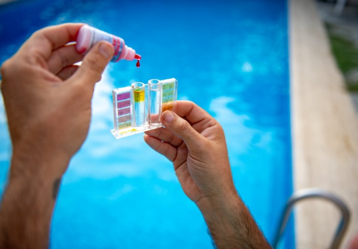 Gros plan sur les mains d'une personne effectuant un test d'eau de piscine.