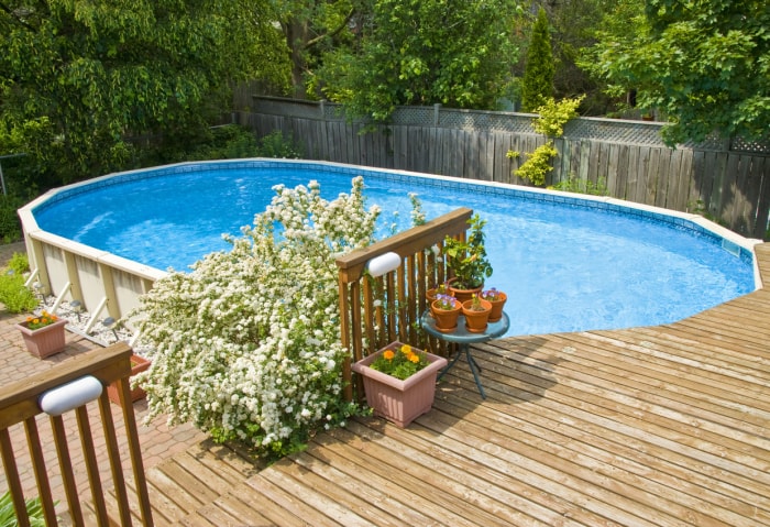 Piscine hors sol encastrée dans la terrasse et entourée de petites pierres de rivière