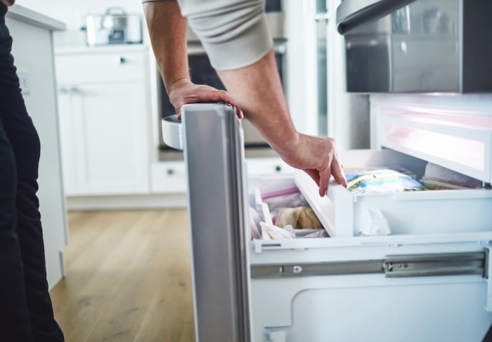 Ouverture d'un tiroir congélateur dans une cuisine familiale.