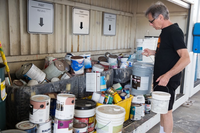 Un homme âgé dépose de vieux pots de peinture au centre de recyclage