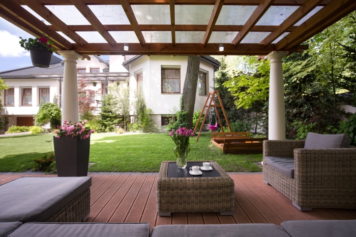 Maison élégante avec pergola à l'arrière avec vitres et meubles de patio.