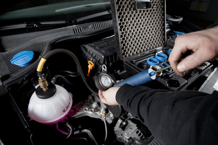 Test d'étanchéité : un mécanicien injecte de l'air dans le système de refroidissement d'une voiture moderne