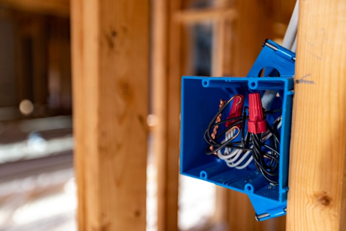 Boîte électrique bleue fixée sur un mur en bois dans une maison en cours de construction.