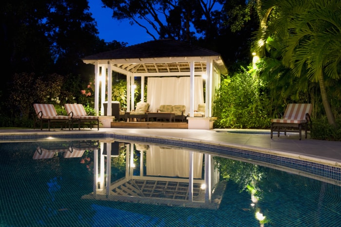 The white and cream colored cabana in a backyard pool.