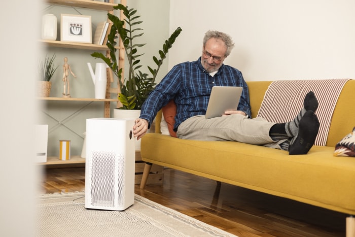 Un homme allume son nouveau purificateur d'air à l'aide d'une tablette numérique