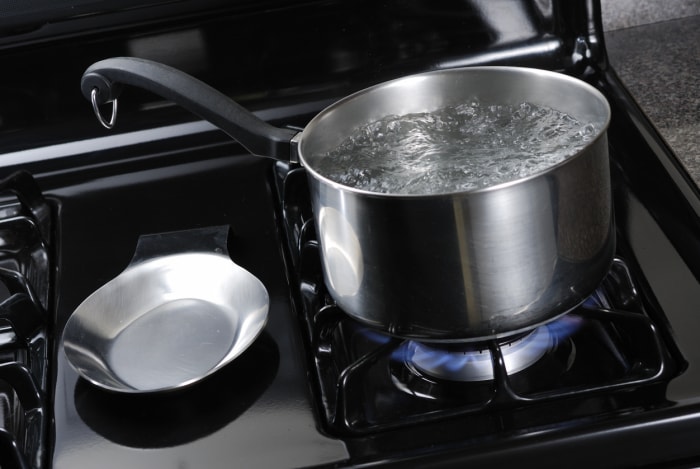 De l'eau bouillante dans une casserole en acier inoxydable sur une cuisinière noire.