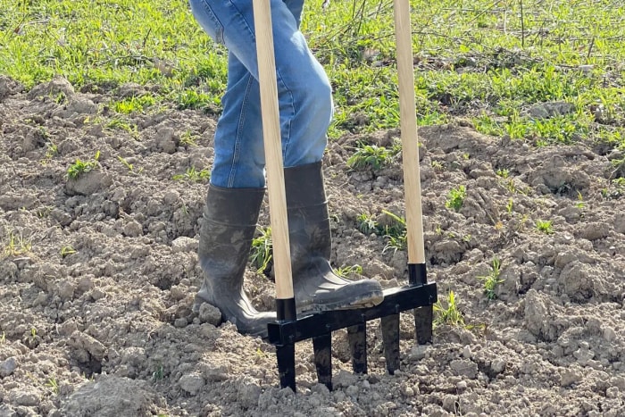 Comment labourer un jardin sans motoculteur - une personne utilise une fourche à larges branches dans le sol