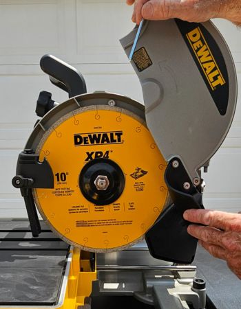 Une personne utilise la fonction de remplacement facile de la lame de la scie à carreaux humide DeWalt de 10 pouces pour changer la lame.