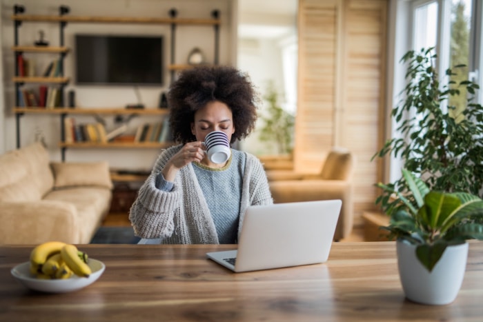 Femme buvant dans une tasse à la table de la cuisine.