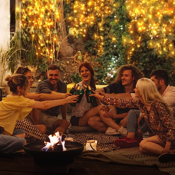 fête de jardin en plein air amusante avec des amis qui boivent et des guirlandes lumineuses accrochées au mur en arrière-plan