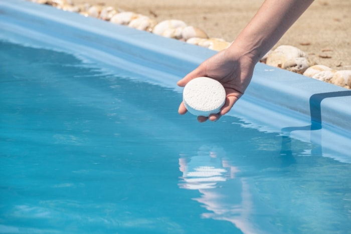 Gros plan d'une personne mettant un produit chimique dans une piscine.