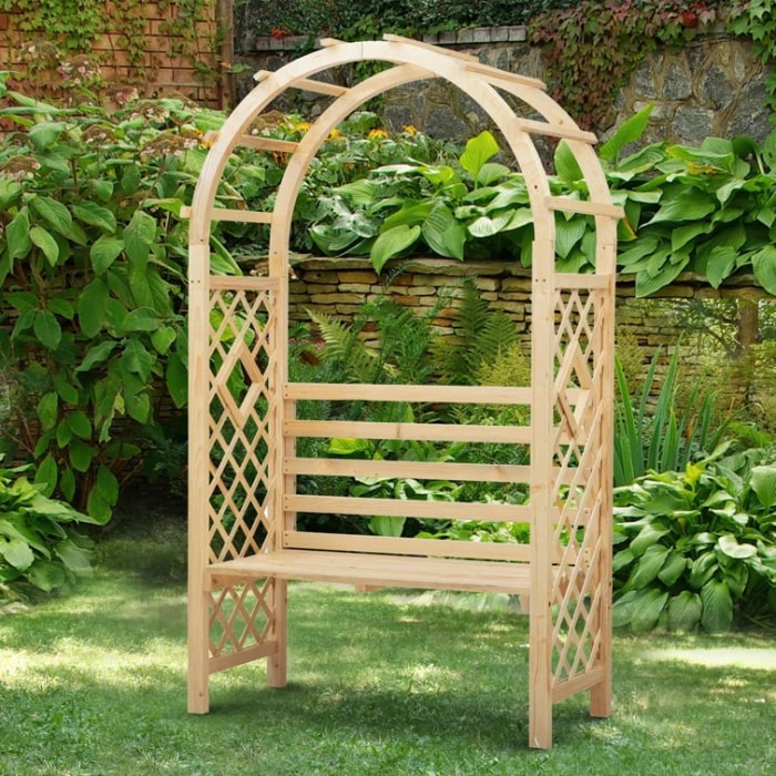 Banc de jardin tonnelle avec arche et entouré de plantes de jardin.