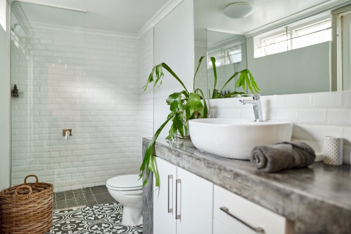 Salle de bain 3/4 avec comptoirs gris et douche avec carrelage blanc.