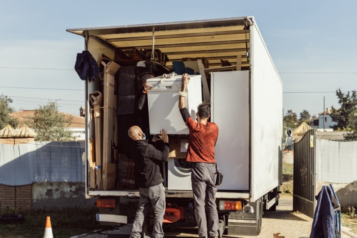 Deux déménageurs chargent un lave-linge dans un camion.