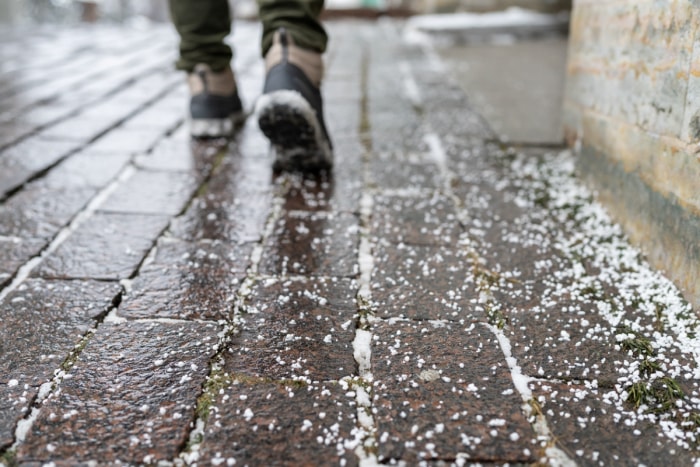 Personne marchant sur un trottoir salé et verglacé.