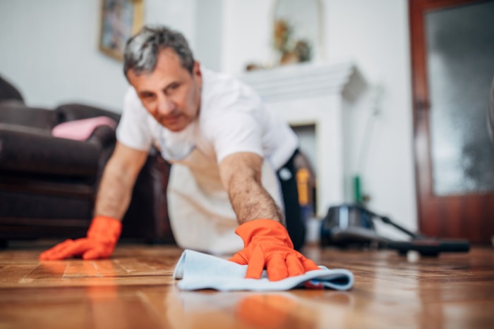 Homme polissant un plancher en bois.