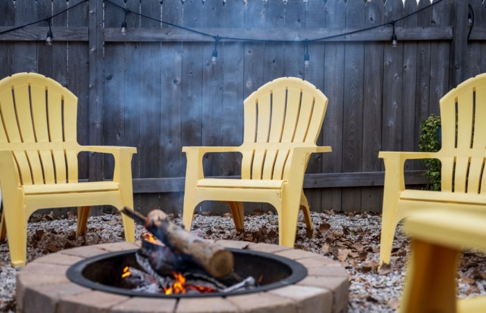 Chaises de jardin jaunes autour d'un foyer enfumé.