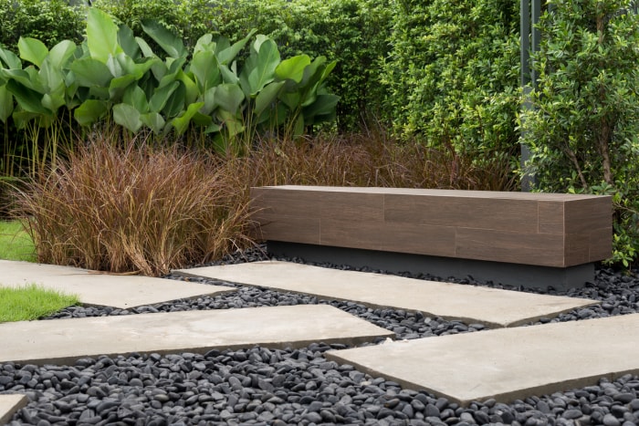 Un banc de jardin en pierre minimaliste dans une cour moderne.