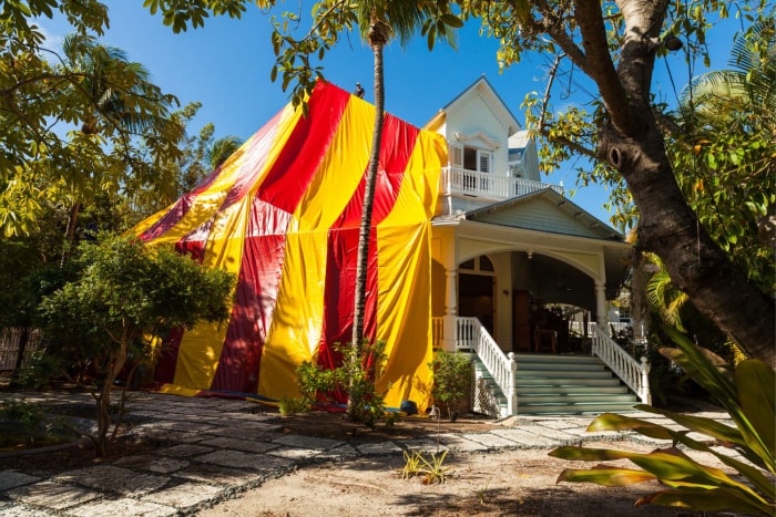 Des ouvriers recouvrent une maison d'une tente rouge et jaune avant la fumigation.