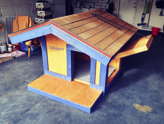 maison de chien diy à l'intérieur du garage avec bardage bleu toit en tuiles et deux portes dont une qui s'ouvre vers le haut