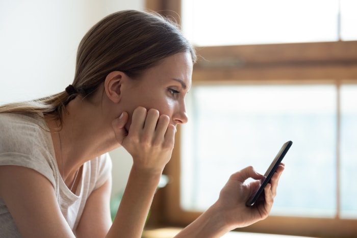 Jeune femme lisant les nouvelles sur son smartphone.