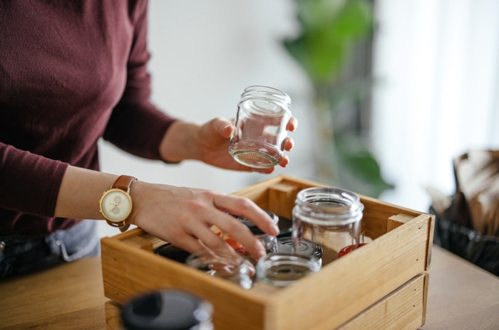 Photo en gros plan des mains d'une femme séparant des pots vides dans une caisse en bois sur le bureau de la cuisine.