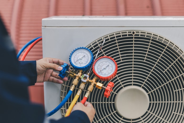 Un technicien HVAC utilise des jauges pour vérifier un climatiseur extérieur.