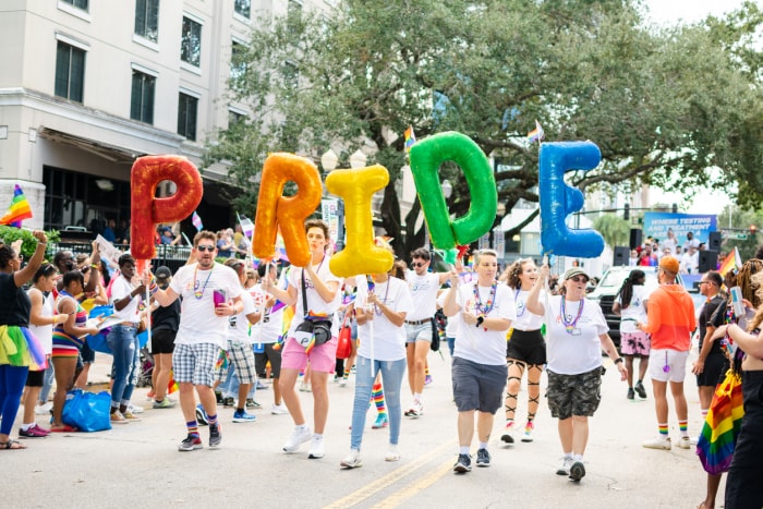 Orlando, Floride, États-Unis, 15 octobre 2022. Groupe de membres de la communauté LGBTIQIA+ et d'employés alliés de Harmony Healthcare Orlando, avec un panneau de fierté coloré lors du défilé Come Out With Pride Orlando 2022, sur la rue E Central Blvd.