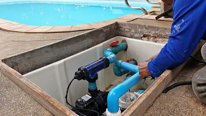 Technicien réparant une pompe à eau de piscine pour piscine d'eau salée.