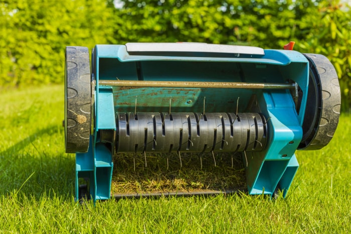 Vue rapprochée d'un aérateur de pelouse électrique sur herbe verte isolée. Concept de machines de jardin.