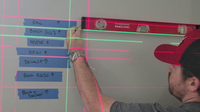 Une personne utilisant un niveau traditionnel pour vérifier la précision de plusieurs des meilleurs niveaux laser lors des tests.