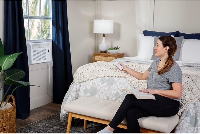 Femme allumant la climatisation de fenêtre avec la télécommande