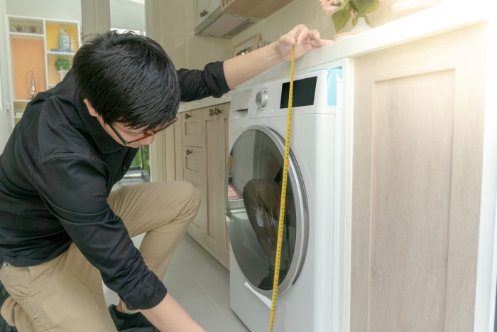 iStock-1035884128 Homme faisant des courses chez Home Depot mesurant la hauteur de la machine à laver