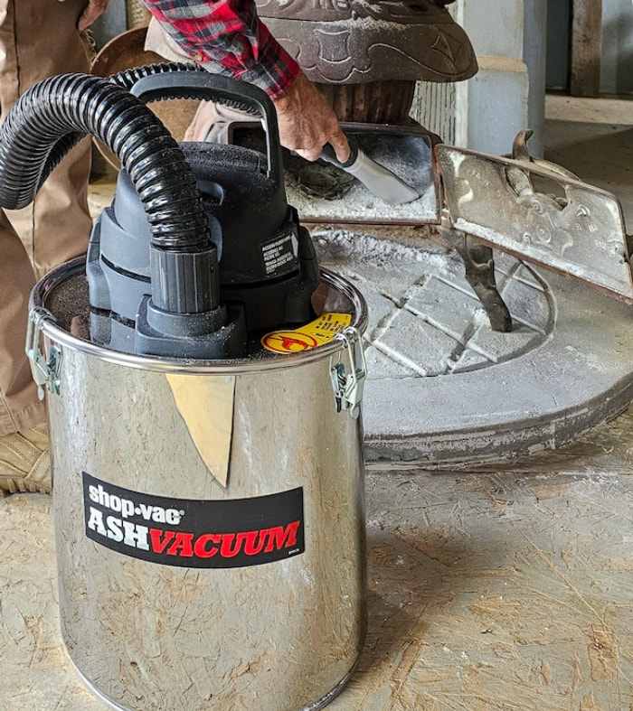 Une personne utilise un aspirateur à cendres pour éliminer les cendres d'une surface.