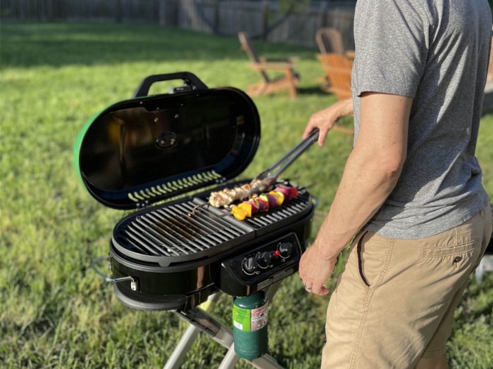 Une personne utilisant le barbecue au propane portatif sur pied Coleman RoadTrip 285 à l'extérieur pendant les tests.