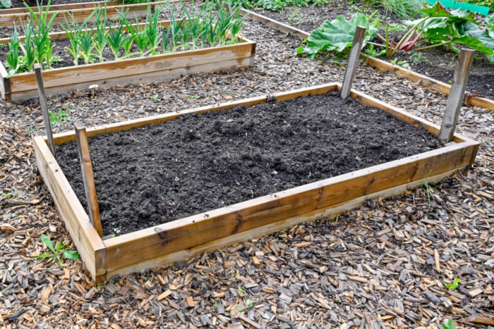 Un lit de jardin surélevé nouvellement construit semble prêt à être planté après avoir été rempli de terre riche.